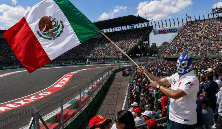 A fan at the Mexican Grand Prix waving a Mexico flag wearing a wrestler mask